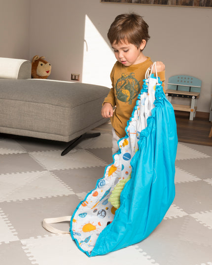 Niño jugando con la manta 2 en 1 de Amamantas, que funciona como alfombra y bolsa, con diseño de espacio.