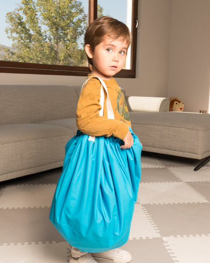Niño pequeño sosteniendo la Manta Niños 2 en 1 de Amamantas, que funciona como alfombra y bolsa, con diseño de espacio.